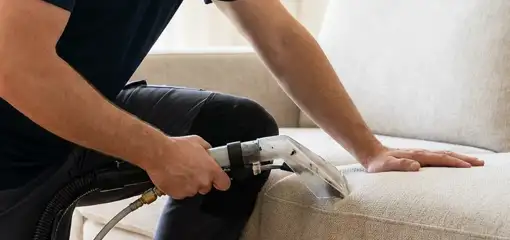 Professional upholstery cleaner deep-cleaning a fabric sofa with a handheld extraction tool, Rockford, IL.
